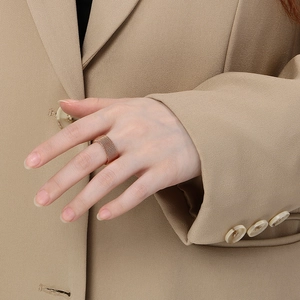 Detail of rose gold woven mesh texture ring shown on model hand with warm aesthetic