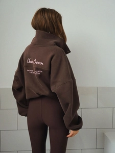 Detail of pink embroidered lettering on the back of a dark brown oversized sweatshirt