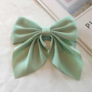 Detailed close-up of mint green silk satin bow hair clip on a minimalist background