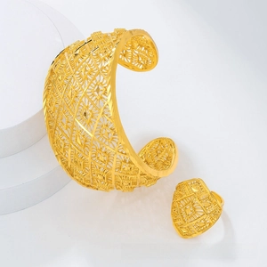 Detail of gold hollow-out jewelry set with intricate geometric patterns on white platform