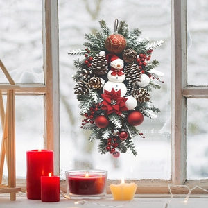 Detail of Christmas wall hanging featuring faux pine branches, pinecones and a snowman figure