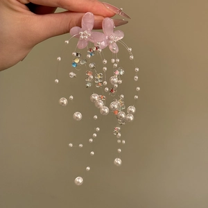 Close-up of sweet pink flower earrings with long white imitation pearl tassels