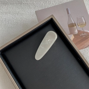 Elegant cream marble textured teardrop hair clip displayed on a luxury black jewelry tray