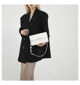 Detail of white crocodile pattern shoulder bag with gold chain strap on model
