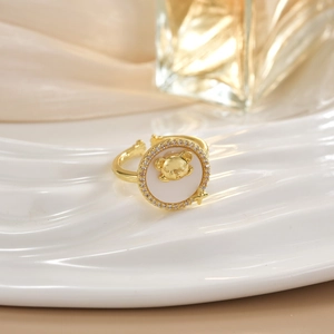 Macro detail of a gold bear relief on white panel ring with crystal pavé setting