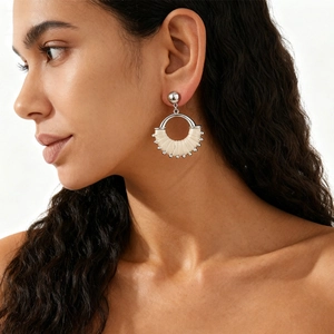 Detail of silver hollow round earrings with cream woven thread and small metallic beads