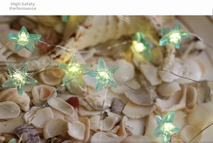 Close-up of blue starfish LED string light with warm glow over assorted sea shells