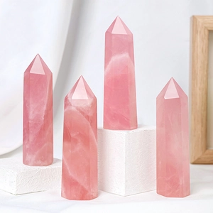 Natural pink rose quartz crystal hexagonal pillars displayed on white textured pedestals