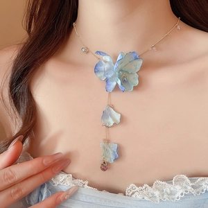 Close-up of a blue fabric flower pendant necklace with purple crystal on a model neck