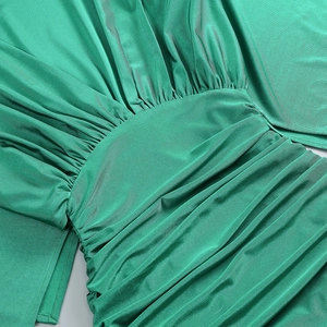 Dettaglio dell'abito verde con maniche a pipistrello, arricciatura in vita e texture satin