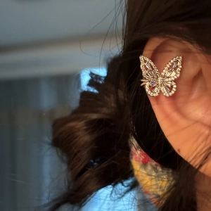 Detailed close-up of a sparkling zircon butterfly ear cuff on a female ear bone clip.