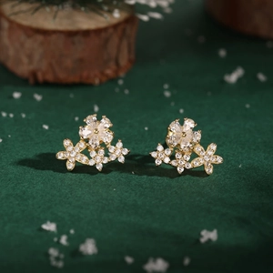 Macro shot of gold S925 silver flower earrings with sparkling cubic zirconia on green velvet