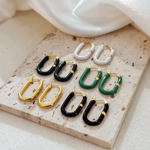 Close-up of colorful enamel U-shaped stainless steel earrings on a textured stone base