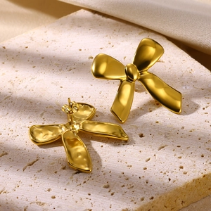 Elegant 18K gold-plated geometric bow stud earrings on a textured stone pedestal