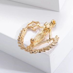 Detailed view of golden Libra zodiac brooch with a stylized figure and scales design