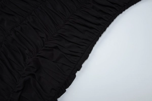 Close-up of ruched black fabric detail showing textured pleats on a bodycon dress