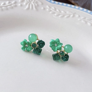 Detailed view of green opal floral earrings with crystals on a vintage ceramic plate