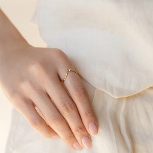 Close-up of golden V-shaped titanium steel ring with birthstone on model finger