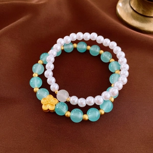 Detail of 2-piece beaded bracelet set with white pearls, blue beads and gold flower charm