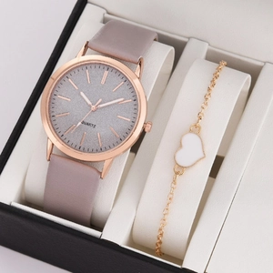 Detail of rose gold quartz watch with pink leather strap and gold heart bracelet in gift box