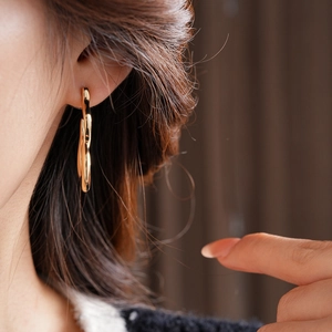 Close-up of golden irregular hoop earrings showing the elegant fit on earlobe