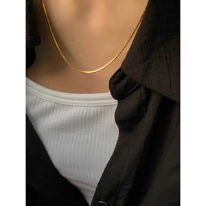 Minimalist gold PVD plated flat snake chain necklace worn by model on black jacket