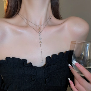 Close-up of elegant double-layer silver star necklace with tassel on model's neck