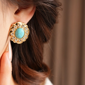 Gros plan d'une boucle d'oreille vintage dorée avec turquoise et petits strass brillants