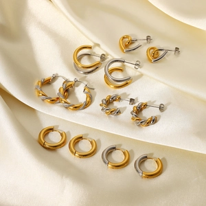 Detailed view of two-tone gold and silver geometric earrings on champagne silk fabric