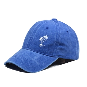 Side view of a washed blue denim baseball cap featuring white palm tree embroidery