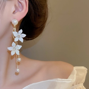 Detail shot of long tassel earrings with white flower petals and dangling pearls