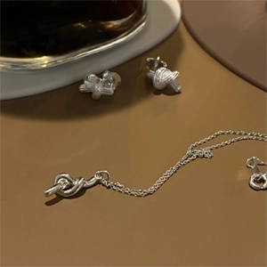 Detailed view of silver knot necklace and matching stud earrings set in a soft lighting