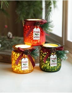 Three glowing Christmas glass LED canisters with festive pine cones and ribbon bows