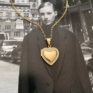 Macro shot of gold heart locket necklace with white zircons on creative artistic background