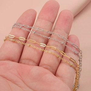 Double-layered stainless steel cross chain bracelets in gold and silver held by hand