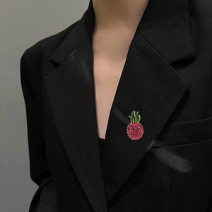 Detail view of a pink pineapple brooch with rhinestones on a black suit lapel