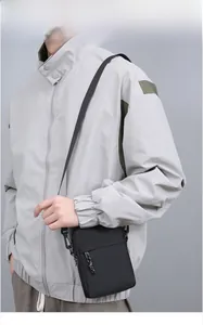 Detail of black nylon crossbody bag with adjustable strap worn on a gray jacket