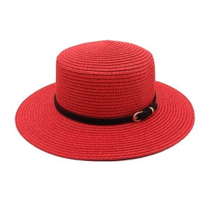 Close-up of red flat top straw boater hat with black leather band and gold buckle