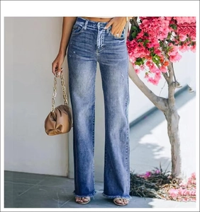 Close-up of distressed denim hem with frayed fringe detail on wide-leg flared jeans