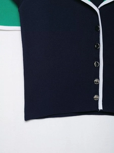 Close-up of knit cardigan with metallic embossed buttons and contrast white piping