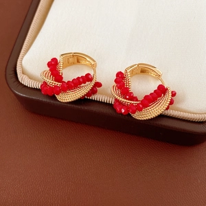 Macro shot of gold twisted hoop earrings with red faceted glass beads on a jewelry box