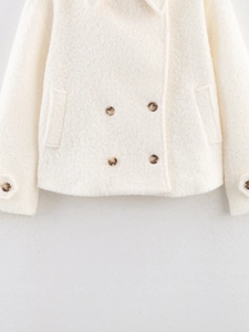 Detail view of cream white sherpa coat featuring double-breasted buttons and side pockets