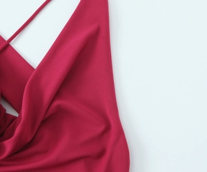 Dettaglio del tessuto fluido dell'abito rosso scuro con spalline sottili a spaghetti