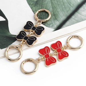 Close-up of red and black enamel bow charms with golden metal ring clasps for bags
