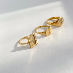 Three-piece gold sunburst ring set featuring radiant solar motifs and cz stone accents