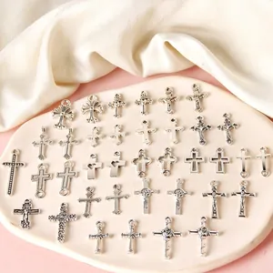 Assorted vintage silver alloy cross pendants for DIY jewelry making on a cream tray