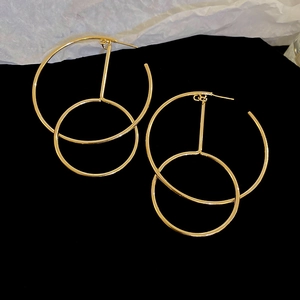 Detail of interlocking gold geometric hoop earrings on black velvet and paper