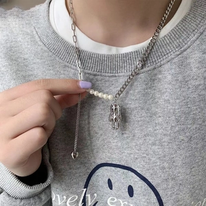 Vue détaillée du pendentif astronaute et cœur argenté sur un collier mixte perles et mailles