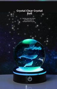 Macro shot of 3D crystal ball showing internal laser-engraved whales under moonlight