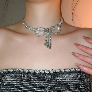 Detail shot of a silver bow necklace with flowing diamond tassels and elegant pearls